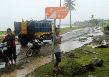 Beberapa pria di tengah hujan di kecamatan Sumur, Provinsi Banten, yang terdampak tsunami, 26 Desember 2018. (Foto: Reuters)