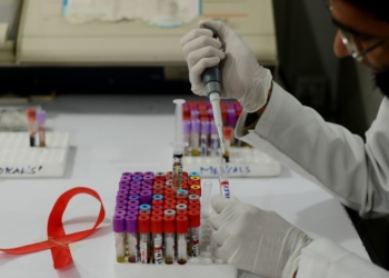 Seorang teknisi Pakistan mengambil sampel di laboratorium sementara tampak di dekatnya pita yang mempromosikan Hari AIDS Sedunia di Islamabad tanggal 30 November 2013 (foto: AFP Photo/Farooq Naeem)