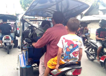 Pengendara bentor bersama seorang anak yang di bonceng, tidak menggunakan helm pengaman.(Foto: Lukman Polimengo)