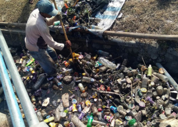 Salah seorang petugas kebersihan tengah mengeluarkan sampah yang menumpuk di saluran air, Desa Toto Utara. Foto: Lukman Polimengo