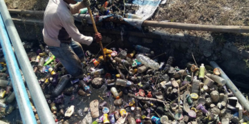 Salah seorang petugas kebersihan tengah mengeluarkan sampah yang menumpuk di saluran air, Desa Toto Utara. Foto: Lukman Polimengo