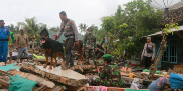 Petugas SAR membawa anjing pelacak untuk mencari korban di antara puing-puing setelah tsunami di Selat Sunda menerjang Rajabasa di Lampung Selatan, 25 Desember 2018. Foto: Reuters