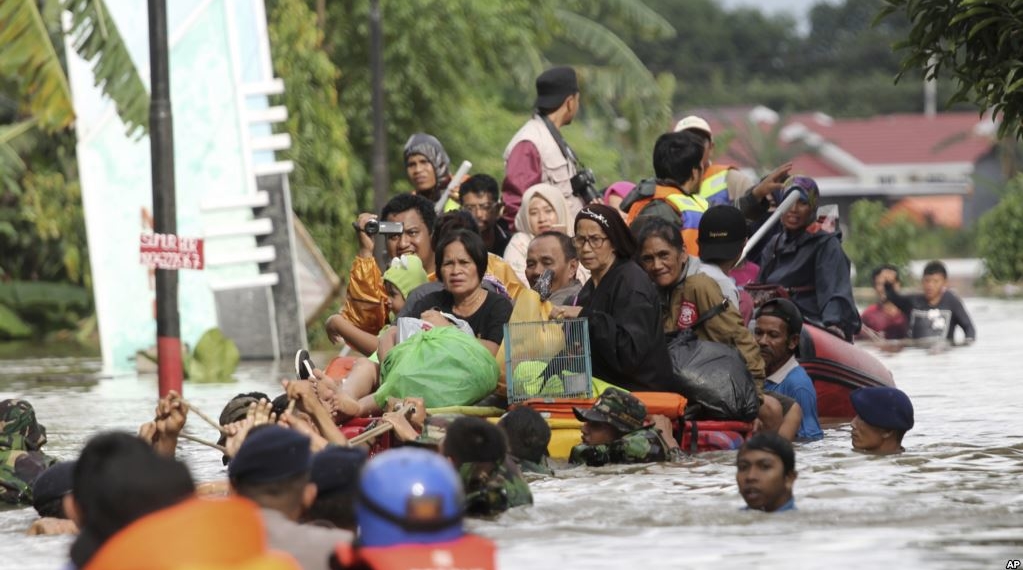 arga naik rakit darurat saat dievakuasi dari rumah kediaman mereka yang terdampak banjir di Makassar, Sulawesi Selatan, 23 Januari 2019.Foto: VOA/AP