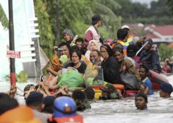arga naik rakit darurat saat dievakuasi dari rumah kediaman mereka yang terdampak banjir di Makassar, Sulawesi Selatan, 23 Januari 2019.Foto: VOA/AP