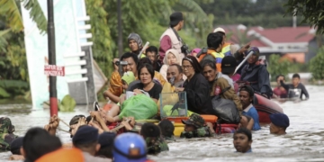 arga naik rakit darurat saat dievakuasi dari rumah kediaman mereka yang terdampak banjir di Makassar, Sulawesi Selatan, 23 Januari 2019.Foto: VOA/AP