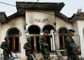 Tentara berjalan melintas sebuah masjid milik pengikut Ahmadiyah yang dibakar massa di Desa Ciampea, Jawa Barat, 2 Oktober 2010.