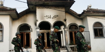 Tentara berjalan melintas sebuah masjid milik pengikut Ahmadiyah yang dibakar massa di Desa Ciampea, Jawa Barat, 2 Oktober 2010.