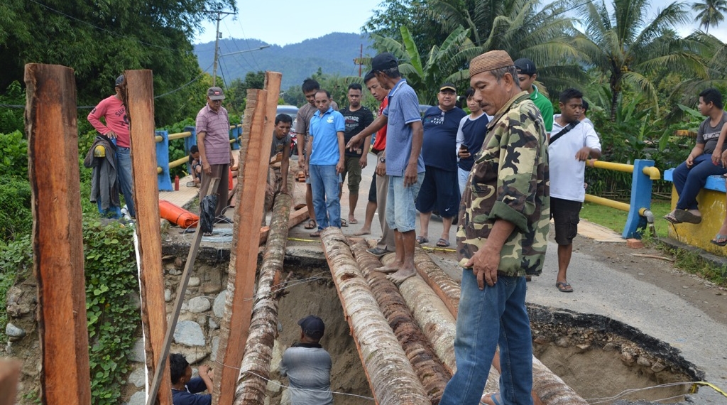 Sejumlah warga bergotong royong membuat jembatan darurat berbahan batang kelapa, pasca jembatan Tolomato yang menghubungkan Kecamatan Suwawa Tengah dan Suwawa Timur ambruk akibat diterjang banjir beberapa waktu yang lalu. Jembatan Tolomato salah satu infrastruktur yang menjadi kewenangan provinsi yang ada di Bone Bolango. (F.dok.AKP)