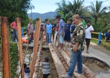 Sejumlah warga bergotong royong membuat jembatan darurat berbahan batang kelapa, pasca jembatan Tolomato yang menghubungkan Kecamatan Suwawa Tengah dan Suwawa Timur ambruk akibat diterjang banjir beberapa waktu yang lalu. Jembatan Tolomato salah satu infrastruktur yang menjadi kewenangan provinsi yang ada di Bone Bolango. (F.dok.AKP)