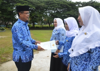 Sekda Ishak Ntoma menyerahkan SK Bupati Bone Bolango kepada 3 orang CPNS formasi dari program PTT Kemenkes tahun 2019 di lingkungan Pemerintah Kabupaten Bone Bolango, pada apel Korpri di halaman Kantor Bupati Bone Bolango, Senin (17/6/2019). (Foto:.AKP)