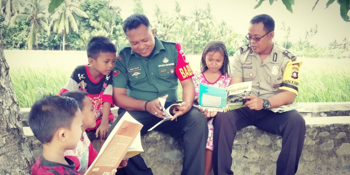 Babinsa Ramil 1304-04/Tapa Kopda Imam Taufik bersama Bhabinkamtibmas Polsek Tapa Brigpol Dede Dwi Kurniawan mengajak anak-anak untuk gemar membaca buku.