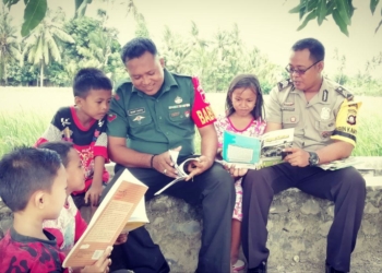 Babinsa Ramil 1304-04/Tapa Kopda Imam Taufik bersama Bhabinkamtibmas Polsek Tapa Brigpol Dede Dwi Kurniawan mengajak anak-anak untuk gemar membaca buku.