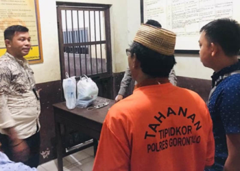 Oknum Kades Monas AS yang mengenakan baju tahanan Tipikor Polres Gorontalo berjalan menuju ke ruang tahanan Polres Gorontalo, Jumat (5/7/2019). (Foto: istimewa)