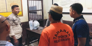 Oknum Kades Monas AS yang mengenakan baju tahanan Tipikor Polres Gorontalo berjalan menuju ke ruang tahanan Polres Gorontalo, Jumat (5/7/2019). (Foto: istimewa)