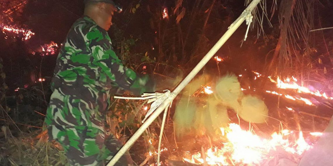 Aparat Babinsa Ramil 1304-06/Suwawa, saat memadamkan kebakaran yang terjadi di sekitar lokasi Pasar Minggu Suwawa Tengah, Selasa (24/9/2019).