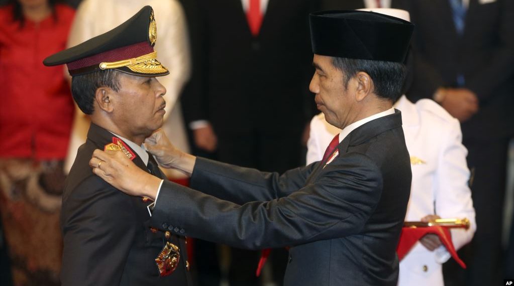 Kepala Kepolisian Republik Indonesia Baru Jenderal Idham Aziz (kiri), menerima lencana baru dari Presiden Indonesia Joko Widodo (kanan), dalam upacara pengambilan sumpah jabatan di Istana Negara, Jakarta, Jumat, 1 November 2019. (AP Foto / Achmad Ibrahim)