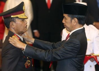 Kepala Kepolisian Republik Indonesia Baru Jenderal Idham Aziz (kiri), menerima lencana baru dari Presiden Indonesia Joko Widodo (kanan), dalam upacara pengambilan sumpah jabatan di Istana Negara, Jakarta, Jumat, 1 November 2019. (AP Foto / Achmad Ibrahim)