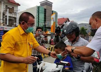 Fikram Salilama, Ketua Fraksi Golkar DPRD Provinsi (Deprov) Gorontalo saat menbagikan masker,kepada warga yang melintas di Bundaran Hulondalo Indah, Minggu (22/3/2020). Foto: Ferdi.
