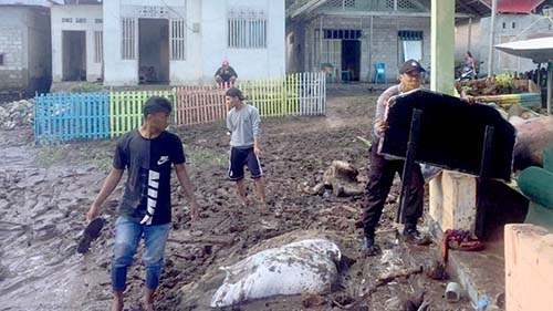 Warga dibantu aparat TNI -Polri, membersihkan sampah dan lumpur yang terbawa air, saat banjir melanda pada Kamis (11/6/2020). Foto Humas Polda Gorontalo.