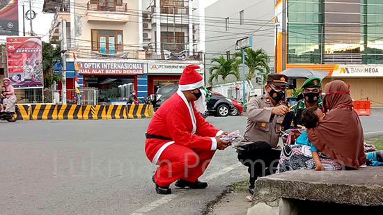 Dalam rangka Operasi Lilin Otanaha 2020, menyambut Hari Natal dan Tahun Baru 2021, jajaran Polres Gorontalo Kota mengadakan kegiatan bagi-bagi masker, dengan mengerahkan personil yang menggunakan kostum Santa Claus. Foto: Lukman Polimengo.