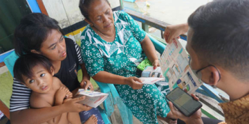 Petugas dari BPJS kesehatan Boalemo tengah menjelaskan manfaat dan penggunaan aplikasi Mobile JKN kepada warga Desa Bajo, Kecamatan Tilamuta. Foto: Lukman Polimengo/mimoza.tv)