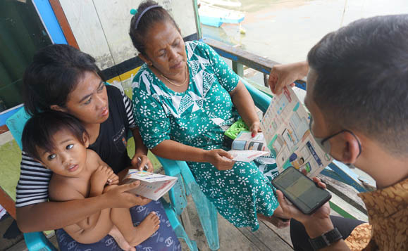 Petugas dari BPJS kesehatan Boalemo tengah menjelaskan manfaat dan penggunaan aplikasi Mobile JKN kepada warga Desa Bajo, Kecamatan Tilamuta. Foto: Lukman Polimengo/mimoza.tv)