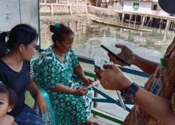 Petugas dari BPJS Kabupaten Boalemo tengah mensosialisasikan penggunaan aplikasi Mobile JKN kepada warga pesisir di Desa Bajo, Kecamatan Tilamuta, Kabupaten Boalemo, Provinsi Gorontalo. (Foto: Lukman Polimengo/mimoza.tv)