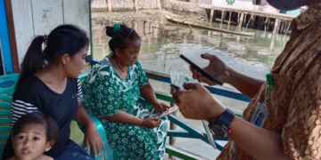 Petugas dari BPJS Kabupaten Boalemo tengah mensosialisasikan penggunaan aplikasi Mobile JKN kepada warga pesisir di Desa Bajo, Kecamatan Tilamuta, Kabupaten Boalemo, Provinsi Gorontalo. (Foto: Lukman Polimengo/mimoza.tv)