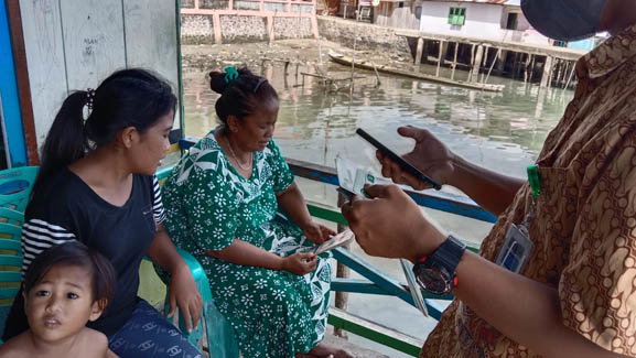 Petugas dari BPJS Kabupaten Boalemo tengah mensosialisasikan penggunaan aplikasi Mobile JKN kepada warga pesisir di Desa Bajo, Kecamatan Tilamuta, Kabupaten Boalemo, Provinsi Gorontalo. (Foto: Lukman Polimengo/mimoza.tv)
