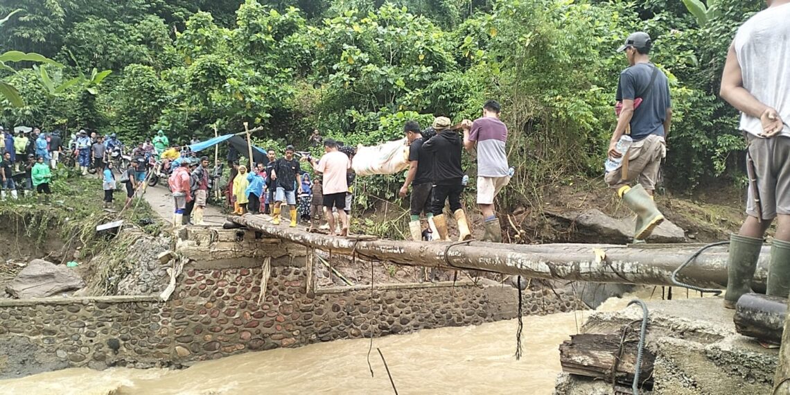 Salah satu korban longsor di area tambang emas Desa Tulabolo Timur, Kecamatan Suwawa Timur, Kabupaten Bone Bolango, tengah dievakuasi melewati jembatan darurat. Foto : Lukman/mimoza.tv.