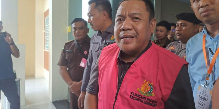 Tersangka STA saat keluar dari Gedung Kejaksaan Negeri Kabupaten Gorontalo mengenakan rompi tahanan, Senin (27/4/2026). STA, mantan Ketua DPRD Kabupaten Gorontalo, ditahan terkait dugaan korupsi Dana Tunjangan Komunikasi Intensif (TKI) periode 2022–2023 yang merugikan negara sekitar Rp3 miliar. (Foto: Andre, untuk mimoza.tv)